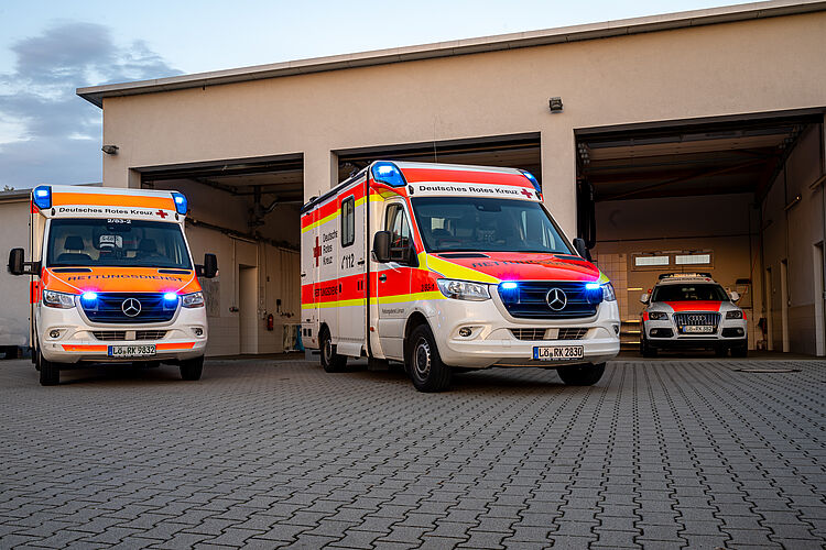 Zwei Rettungswagen und ein Notarzteinsatzfahrzeug mit Blaulicht in der Garage