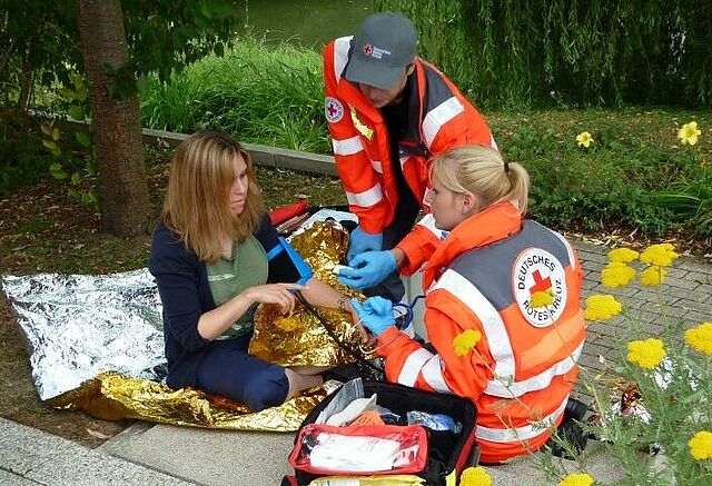 Zwei Helfer des Sanitätsdienst versorgen eine junge Frau